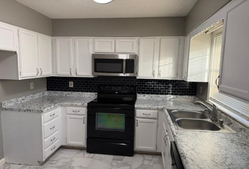 Kitchen with black appliances, white cabinetry, light marble finish floors, a textured ceiling, and decorative backsplash