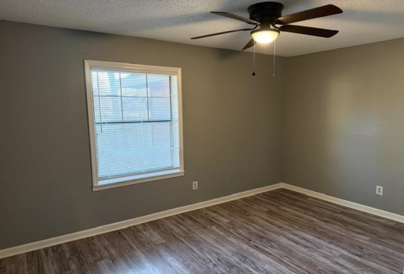 Empty room featuring dark wood-style flooring, a textured ceiling, and ceiling fan
