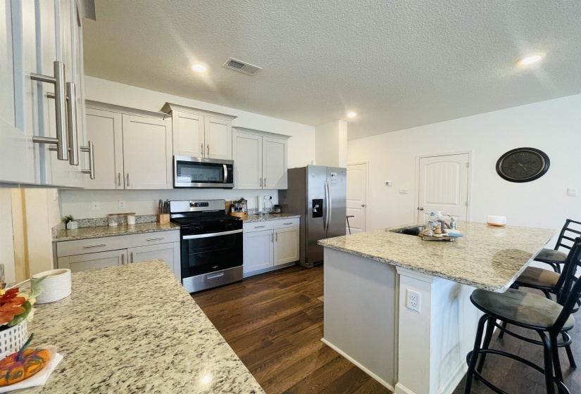 Kitchen with a breakfast bar, stainless steel appliances, a kitchen island, light stone countertops, and a textured ceiling