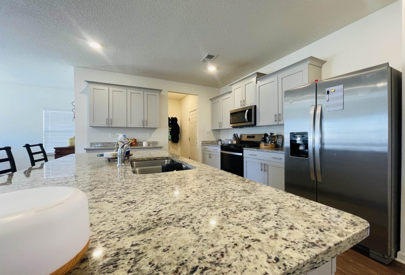 Kitchen with appliances with stainless steel finishes, gray cabinets, light stone countertops, a textured ceiling, and recessed lighting
