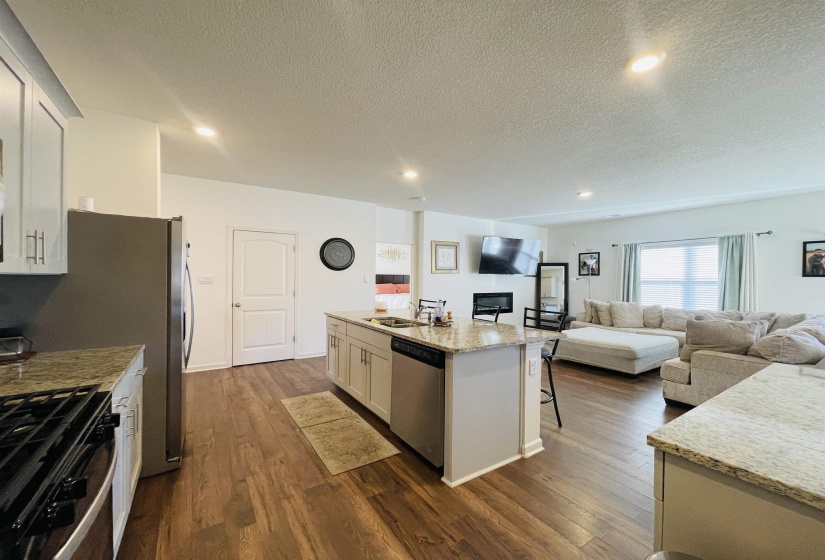 Kitchen with a kitchen bar, white cabinets, open floor plan, recessed lighting, and a textured ceiling
