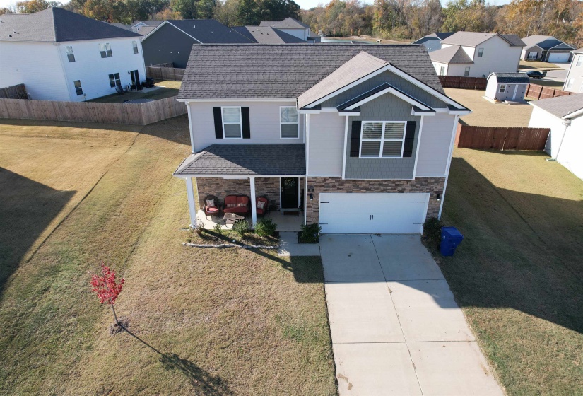 View of front facade featuring stone siding, a shingled roof, a residential view, a garage, and driveway