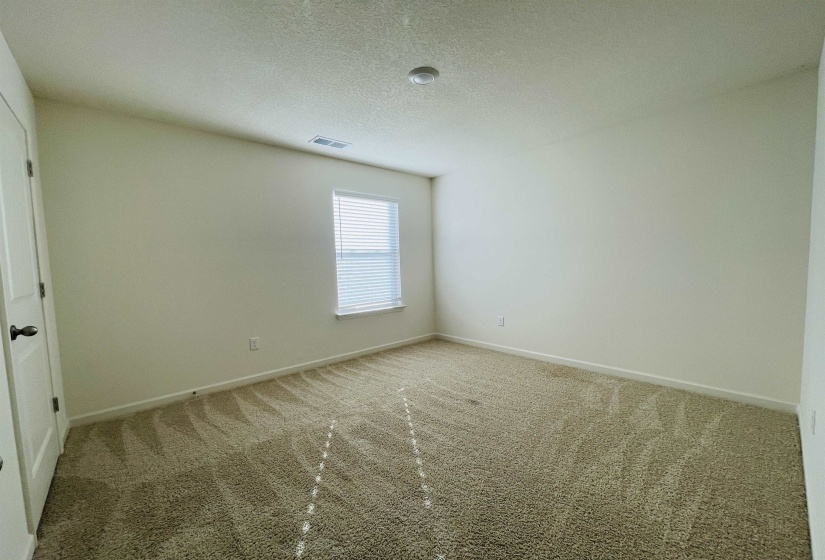 Carpeted empty room with a textured ceiling and baseboards