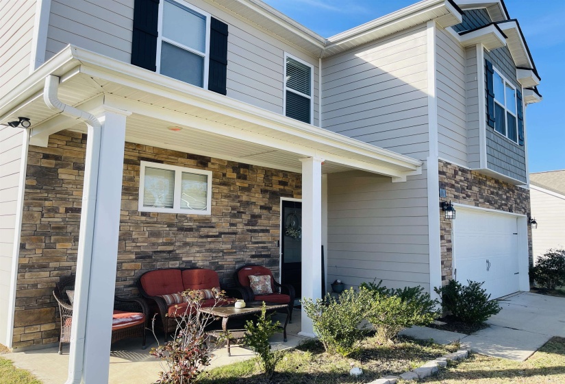 View of front of home featuring stone siding, a garage, and a porch