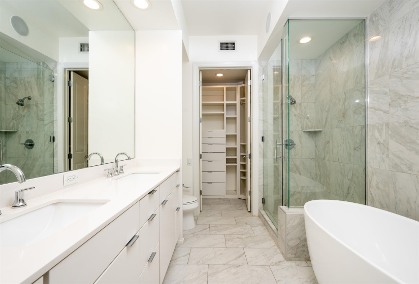 Bathroom with double vanity, a freestanding tub, a shower stall, light marble finish flooring, and recessed lighting
