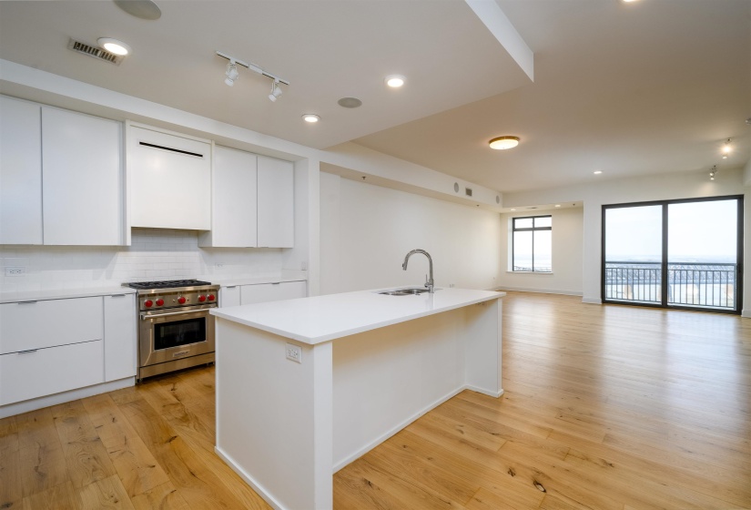 Kitchen featuring white cabinetry, premium range, backsplash, light wood-style flooring, and modern cabinets