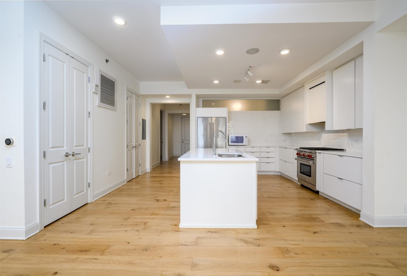 Kitchen with white cabinetry, backsplash, premium appliances, modern cabinets, and a center island with sink