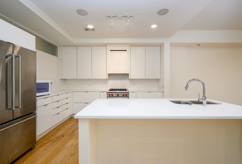 Kitchen featuring high quality appliances, a kitchen island with sink, modern cabinets, and white cabinetry