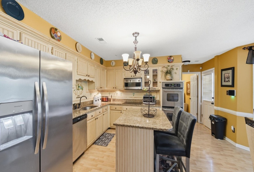 Kitchen featuring appliances with stainless steel finishes, a center island, a breakfast bar, light stone countertops, and a textured ceiling