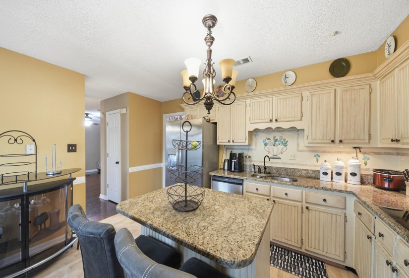 Kitchen featuring a kitchen island, cream cabinetry, light stone counters, a kitchen bar, and a textured ceiling