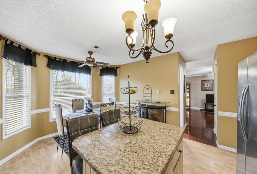 Dining room featuring light wood-style flooring, a chandelier, ceiling fan, and a textured ceiling