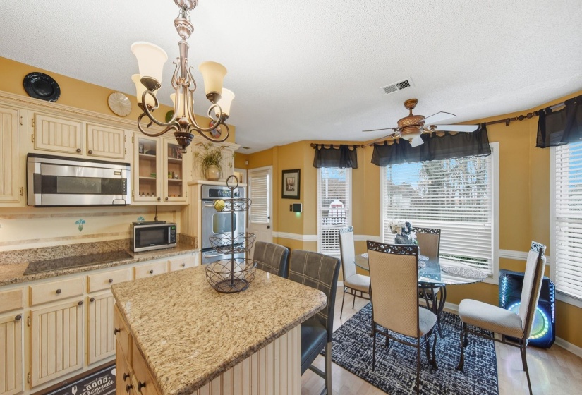 Kitchen with cream cabinetry, a kitchen island, light stone counters, stainless steel appliances, and a breakfast bar