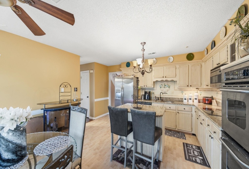 Kitchen with a kitchen island, a chandelier, cream cabinetry, stainless steel appliances, and a textured ceiling