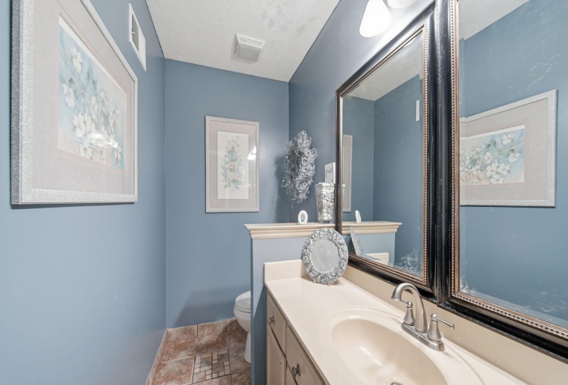 Half bathroom featuring stone tile floors, vanity, and a textured ceiling