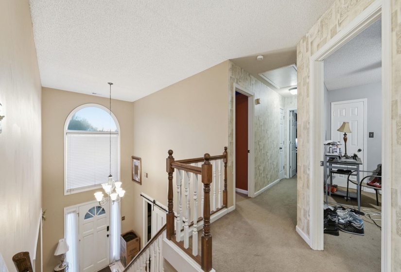 Hall featuring an upstairs landing, a textured ceiling, and light colored carpet