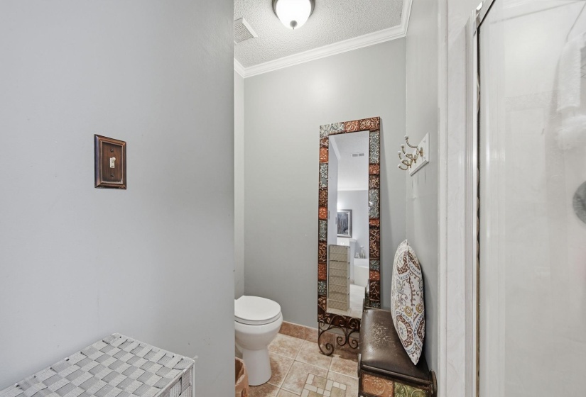 Bathroom with a textured ceiling, crown molding, and light tile patterned floors