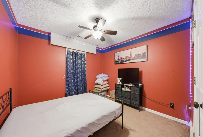 Carpeted bedroom with a textured ceiling and ceiling fan