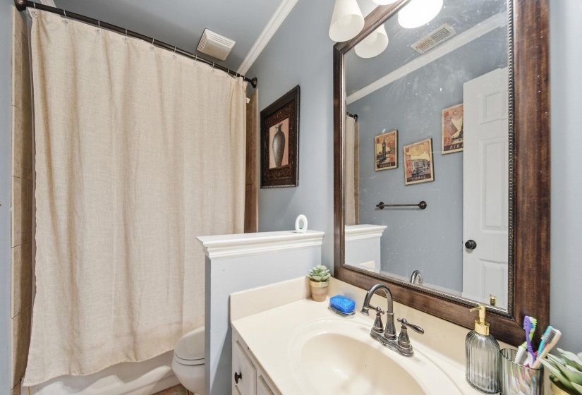 Full bath featuring crown molding, vanity, and shower / tub combo