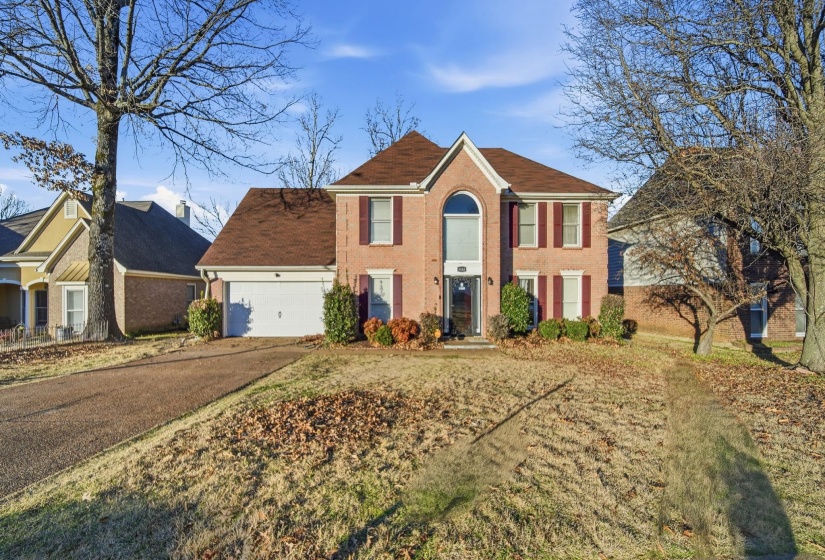 Colonial-style house with driveway, brick siding, and a garage
