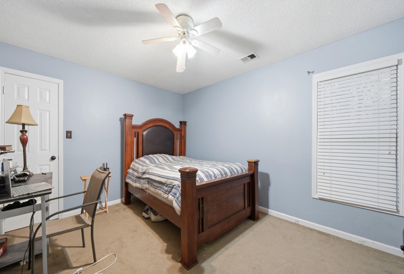 Bedroom with a textured ceiling, light colored carpet, and a ceiling fan