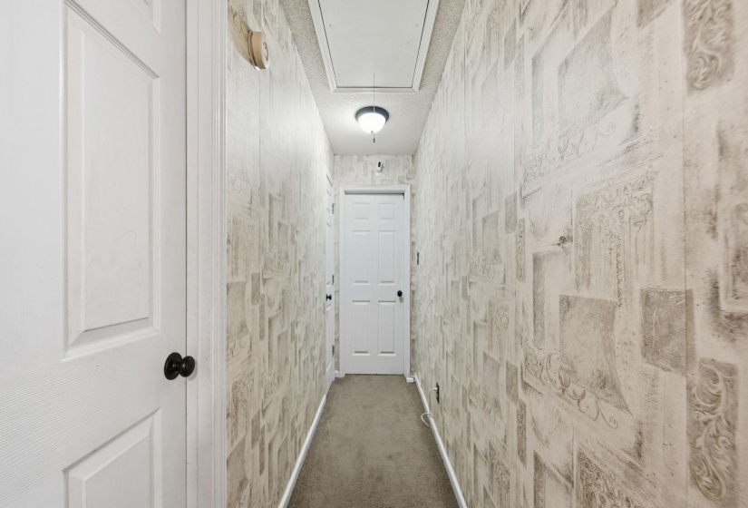 Hall featuring attic access, carpet, and a textured ceiling