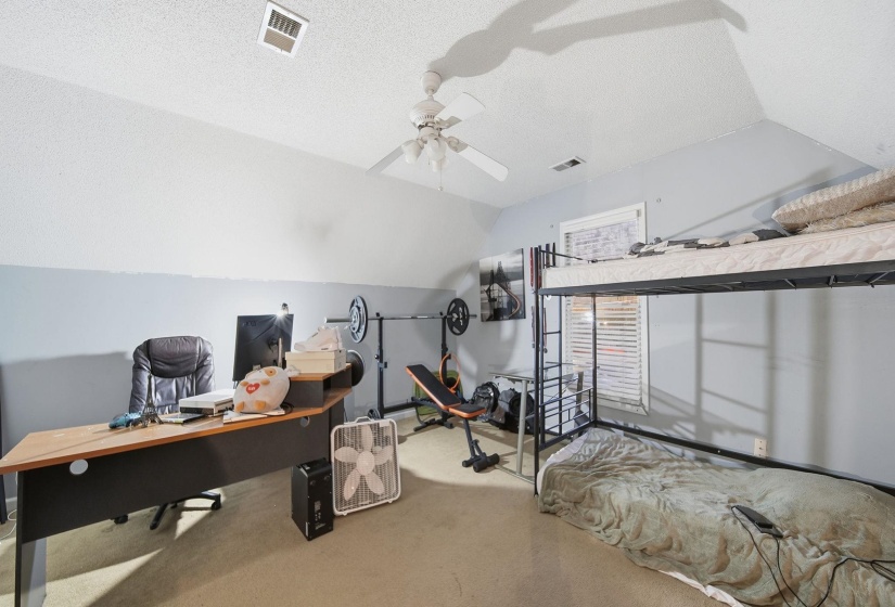 Bedroom featuring vaulted ceiling, a textured ceiling, carpet, an office area, and ceiling fan