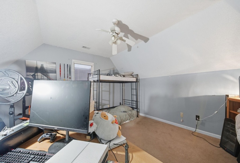 Bedroom with vaulted ceiling, carpet, ceiling fan, and a textured ceiling