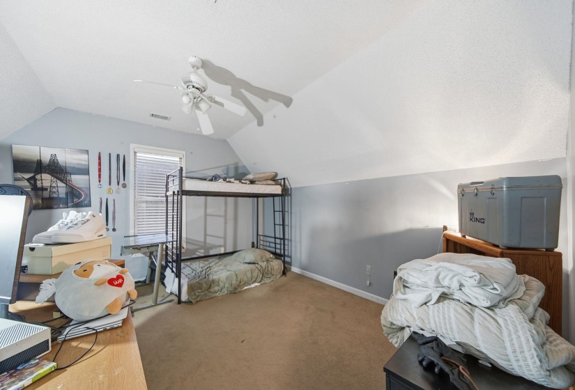 Carpeted bedroom with lofted ceiling, a ceiling fan, and a textured ceiling