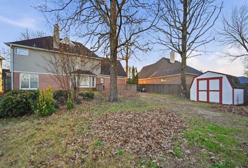 Rear view of property with brick siding, a shed, and a chimney