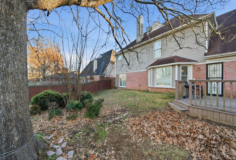 View of side of property featuring a wooden deck, a chimney, a fenced backyard, and brick siding