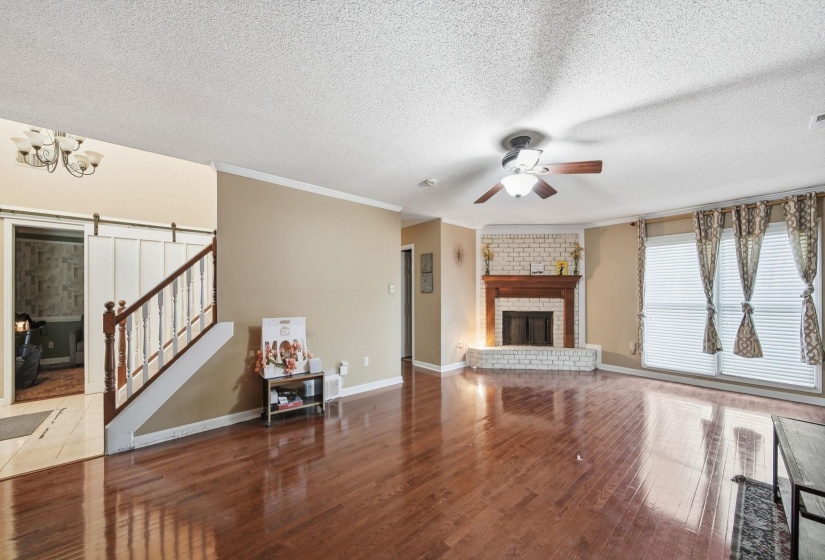 Living room with stairs, a barn door, hardwood / wood-style floors, a textured ceiling, and a fireplace