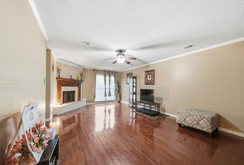Living area featuring ornamental molding, dark wood-style flooring, a fireplace, a textured ceiling, and ceiling fan