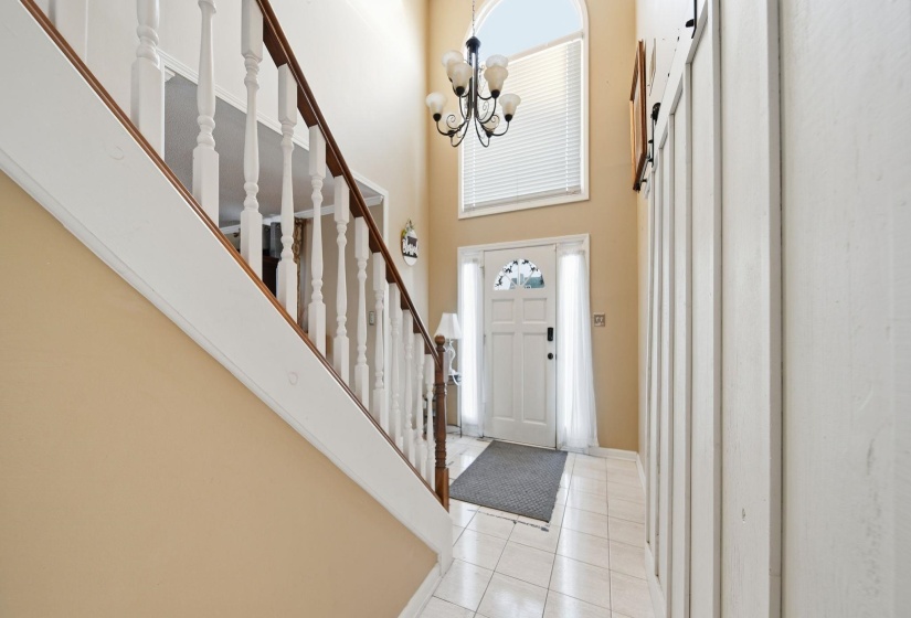 Entrance foyer featuring a high ceiling, tile patterned flooring, stairway, and a chandelier