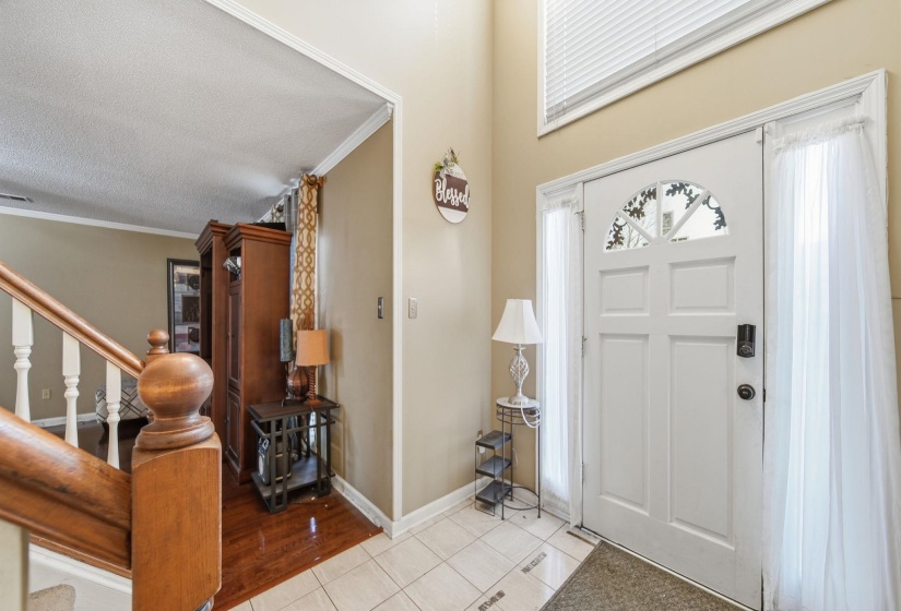 Foyer featuring stairs, crown molding, light tile patterned floors, and a textured ceiling