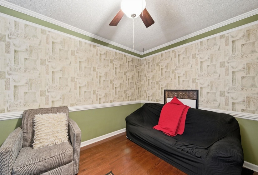 Living area featuring crown molding, a textured ceiling, wood finished floors, and a ceiling fan