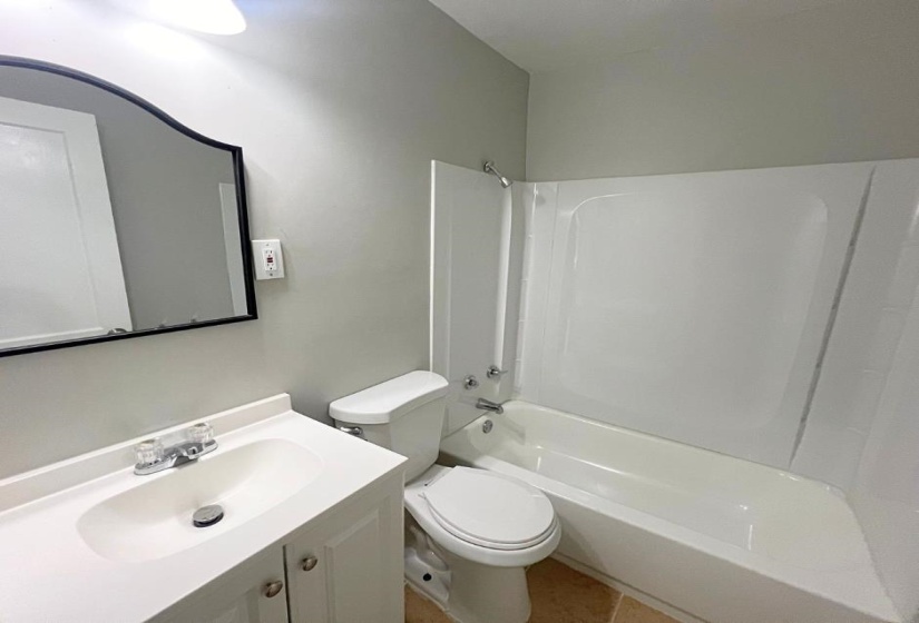 Full bath featuring  shower combination, toilet, vanity, and tile patterned floors