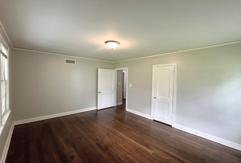 Spare room with ornamental molding, dark wood-style flooring, and baseboards