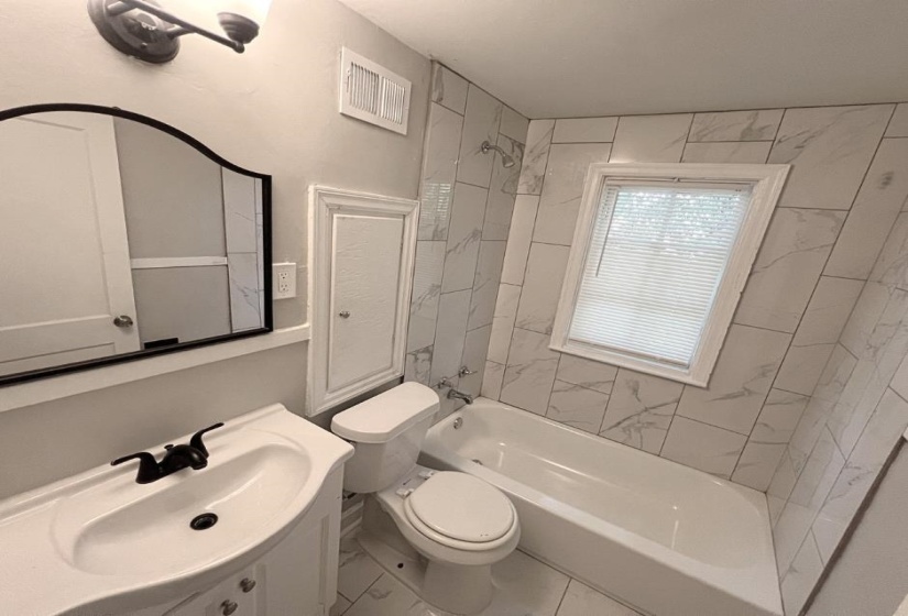 Full bath with washtub / shower combination, toilet, and vanity
