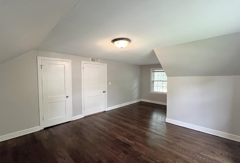 Bonus room featuring lofted ceiling, dark wood finished floors, and baseboards