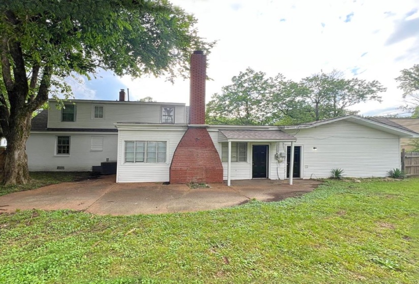 Rear view of property featuring a lawn, a patio area, a chimney, and cooling unit