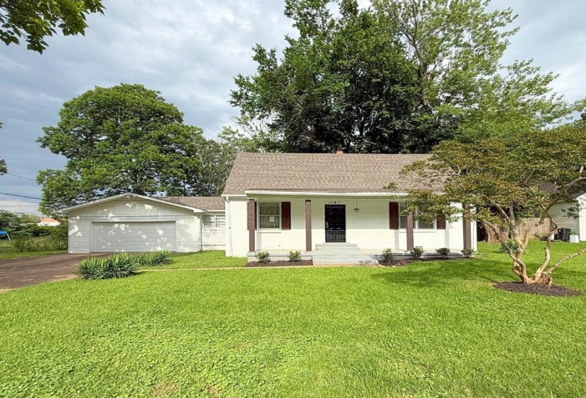 Single story home with a porch, driveway, a front yard, roof with shingles, and an attached garage