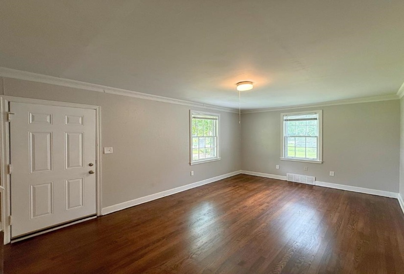 Unfurnished room featuring healthy amount of natural light, crown molding, dark wood-style floors, and baseboards