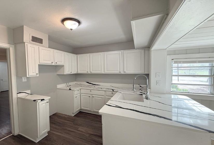 Kitchen featuring a sink, dark wood-type flooring, white cabinetry, and light countertops