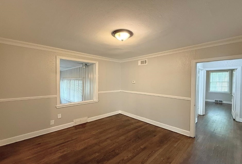 Spare room with dark wood finished floors, crown molding, a textured ceiling, and baseboards