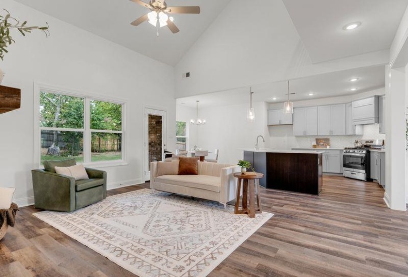Living room featuring high vaulted ceiling, dark wood-style flooring, and a ceiling fan
