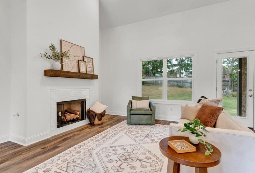 Living room with a fireplace, wood finished floors, and a towering ceiling