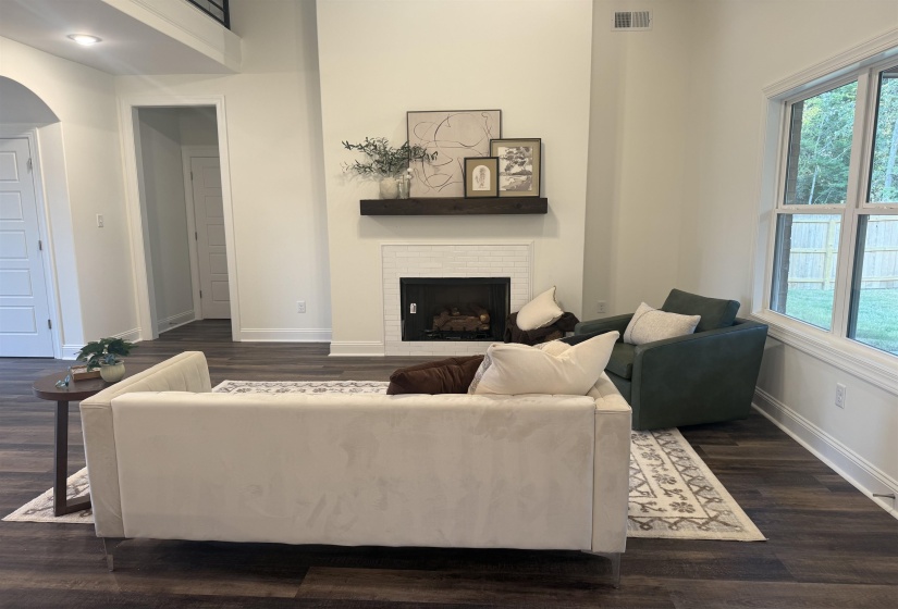 Living area featuring dark wood-style flooring, a fireplace, and arched walkways