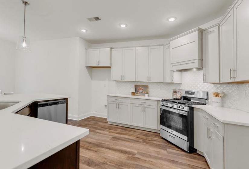 Kitchen featuring stainless steel appliances, light wood-type flooring, backsplash, recessed lighting, and pendant lighting