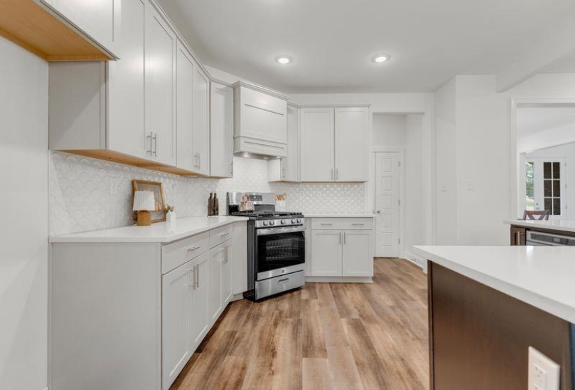 Kitchen featuring stainless steel gas range, tasteful backsplash, light wood-style flooring, white cabinets, and recessed lighting