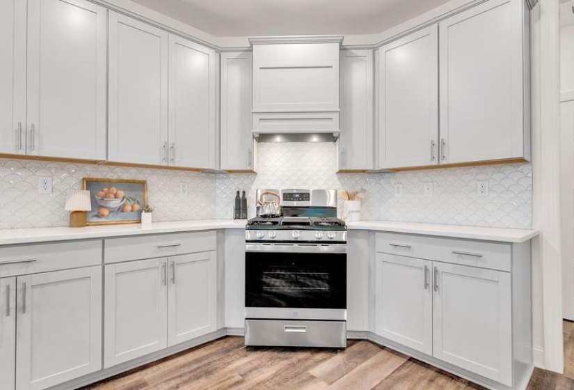 Kitchen with stainless steel gas range oven, tasteful backsplash, and light wood-style flooring